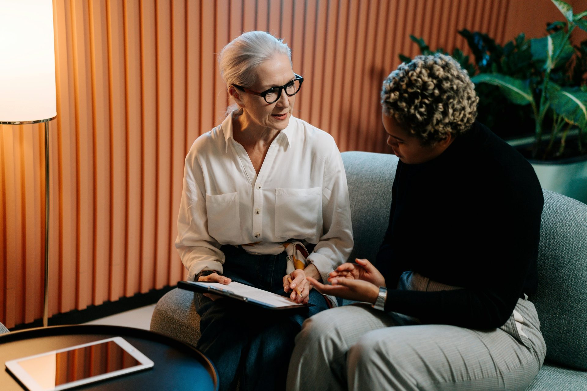 Two professional women engaged in a business discussion indoors with documents.