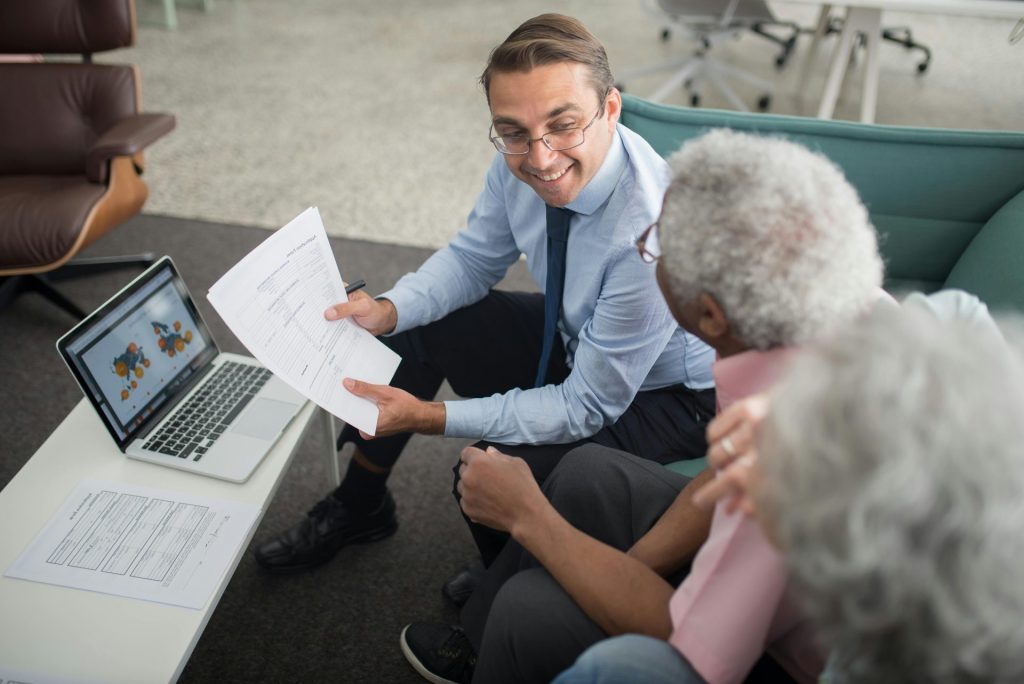 Financial advisor discussing documents with senior clients in an office setting, showcasing a collaborative consulting session.